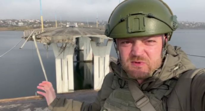 Военкор Александр Коц на фоне разрушенного Антоновского моста